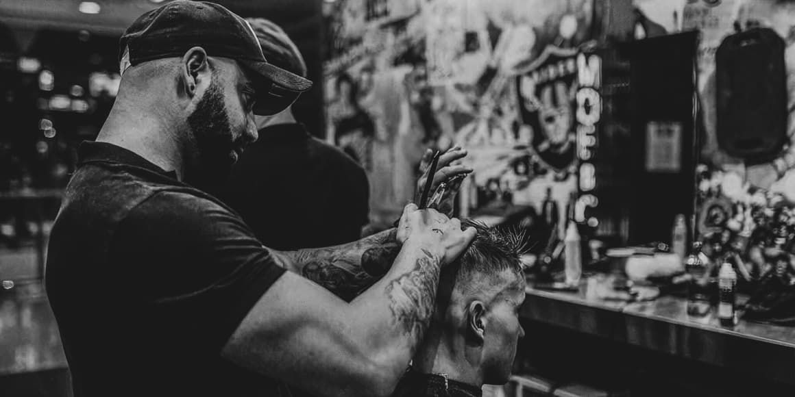 barber cutting men hair with scissors